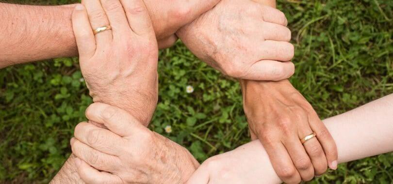 Multiple people's hand grabbing another person's wrist to form a ring.