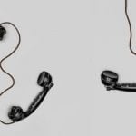 Three black handset phones with cords.