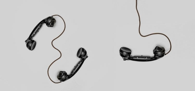 Three black handset phones with cords.