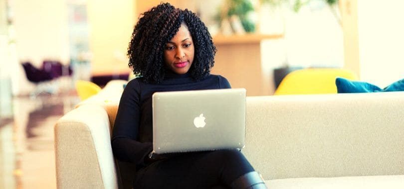 A student sitting on a couch with a laptop.
