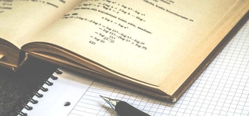 A math textbook open on top of a notebook.