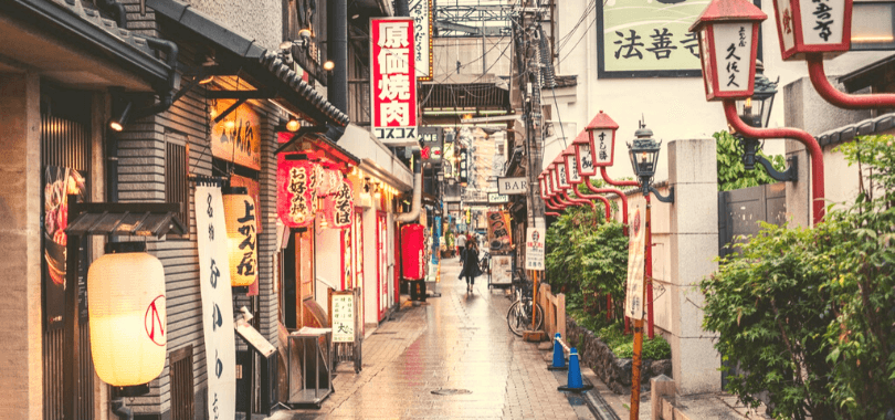 A person walking down a street filled with shops.