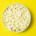 A bowl of popcorn against a yellow background.