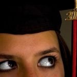 A student wearing a graduation cap looking to the tassel.