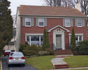 Red brick house with a car parked outside.
