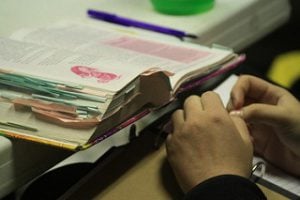 A student studying a text book filled with sticky notes.