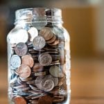 A jar of coins, mostly pennies and dimes.