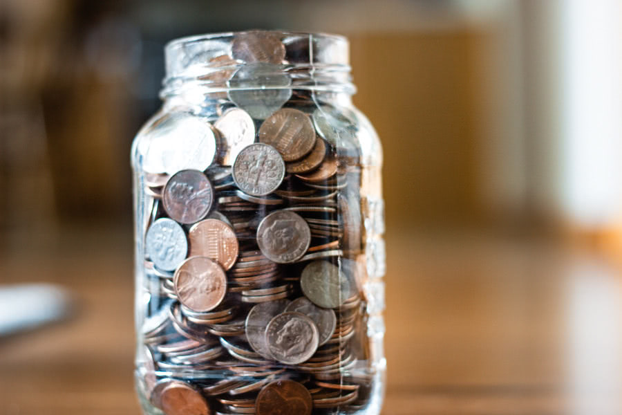 A jar of coins, mostly pennies and dimes.