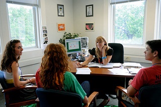 Three students meeting with their academic advisor inside her office.