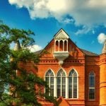 The front of a building on a college campus with trees surrounding it.