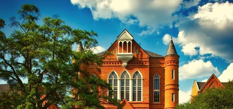 The front of a building on a college campus with trees surrounding it.