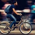 A student riding a bicycle down a street.