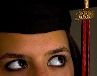 A student wearing a graduation cap looking to the tassel.