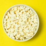 A bowl of popcorn against a yellow background.