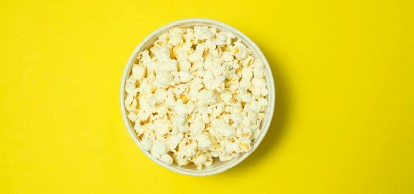 A bowl of popcorn against a yellow background.