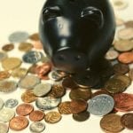 A piggy bank standing on top of a pile of coins.