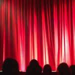 A red theater curtain lit by spotlights.