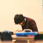 A high school student sitting in a classroom working on an assignment.