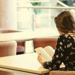 A student sitting at a desk, reading a book.