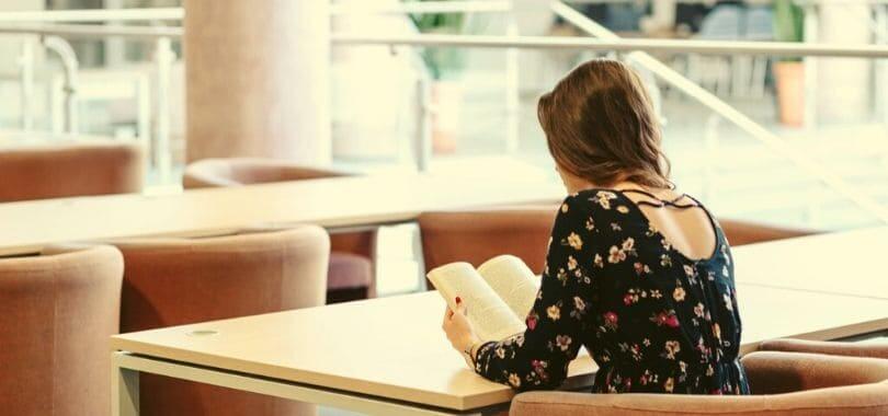 A student sitting at a desk, reading a book.