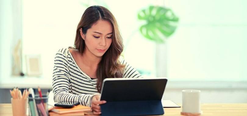 A first generation student sitting at a desk using a tablet.