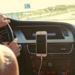 A student driving a car with their phone attached to the dashboard.