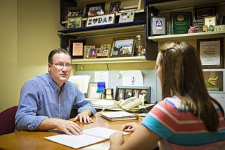 A professor talking to a student in their office.