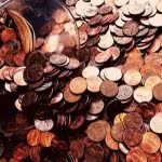 A coin jar with pennies and dimes spilling out of it.