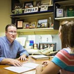 A professor talking to a student in their office.