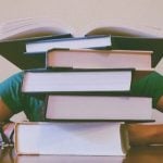 A student sitting behind a pile of books.