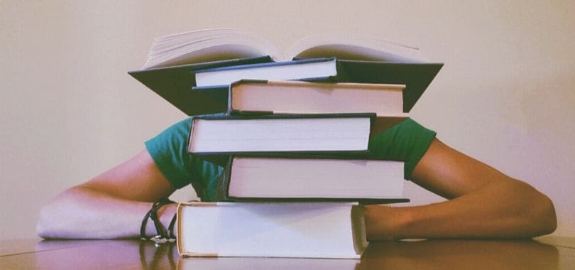 A student sitting behind a pile of books.