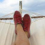 A student relaxing on a hammock wearing red sneakers.