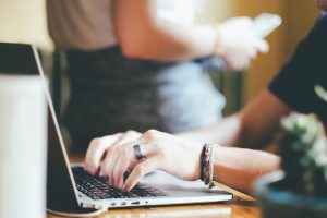 A hand is typing on a laptop.