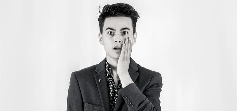 A student looking shocked with a hand on their face.