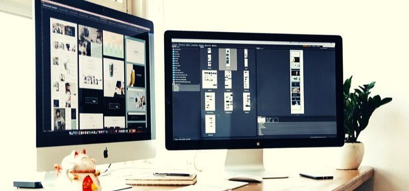 Two computer monitors on a white desk.