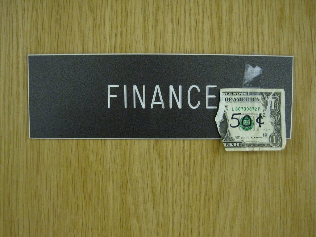 Ripped one dollar bill over a finance signage.