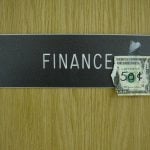 Ripped one dollar bill over a finance signage.