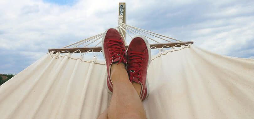 A student relaxing on a hammock wearing red sneakers.