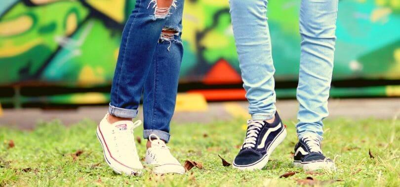 Two students standing together on a lawn.