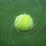 A tennis ball spinning with a darker green background.