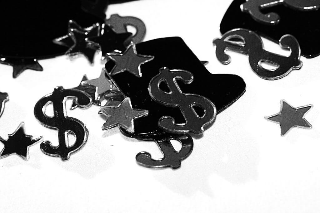 Black dollar sign, stars and hats confetti macro shot.