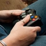 A student's hand holding a game controller.