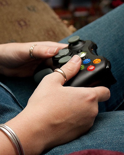 A student's hand holding a game controller.