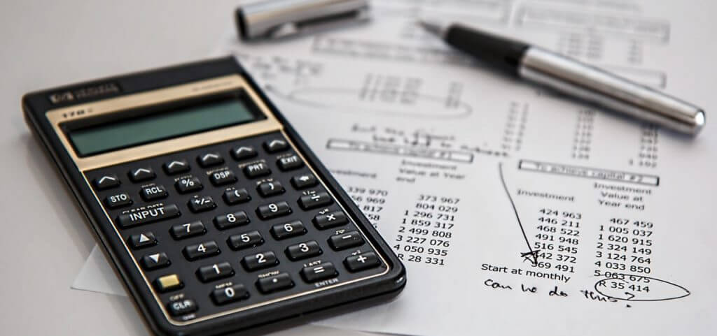 A calculator and pen sitting on top of a piece of paper.