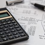 A calculator and pen sitting on top of a piece of paper.