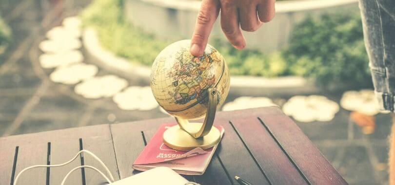 A small globe on top of a passport.