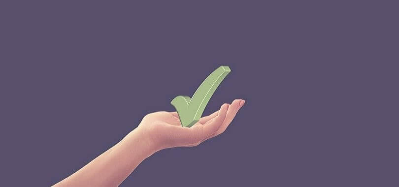 A hand holding a green check mark.
