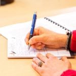 A student writing down on a notebook.