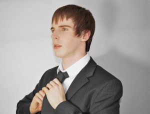 A man fixing his necktie while looking away.