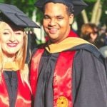 Two students graduating, wearing black graduation robes.